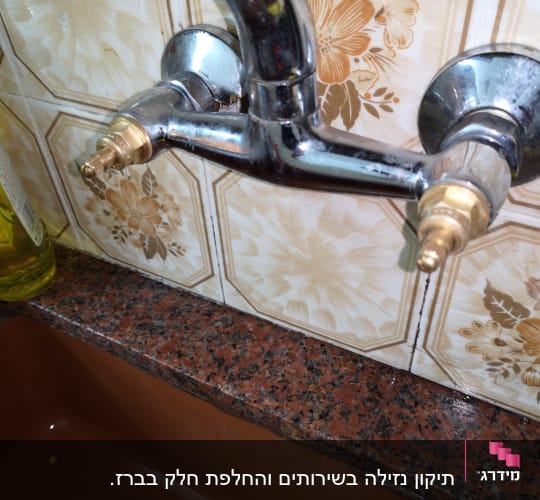 ברז מטבח עם חיבורים חשופים על קיר קרמיקה